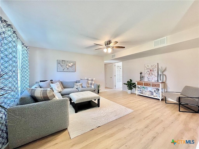 living room featuring wood finished floors, visible vents, and ceiling fan