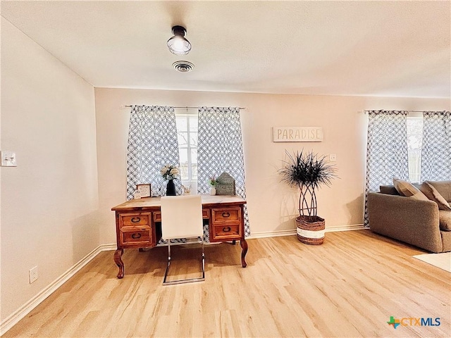 home office with visible vents, a healthy amount of sunlight, baseboards, and wood finished floors