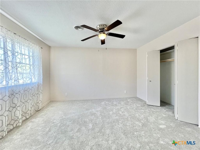 unfurnished bedroom featuring baseboards, a textured ceiling, carpet, and a ceiling fan