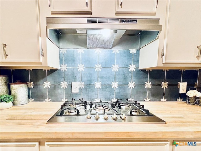 kitchen featuring stainless steel gas cooktop, light countertops, under cabinet range hood, white cabinetry, and tasteful backsplash