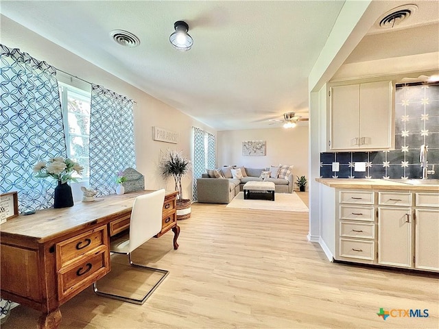 kitchen featuring white cabinetry, a ceiling fan, visible vents, and light wood-type flooring