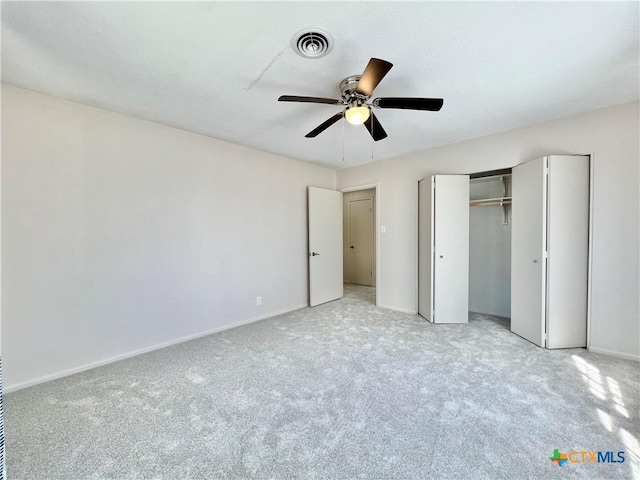 unfurnished bedroom featuring visible vents, a closet, baseboards, light colored carpet, and ceiling fan