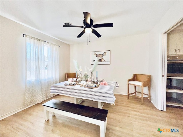 dining space with a ceiling fan and light wood-type flooring