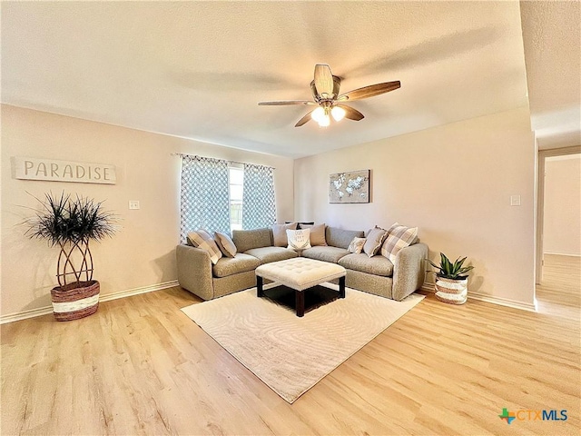 living room featuring a textured ceiling, wood finished floors, baseboards, and ceiling fan