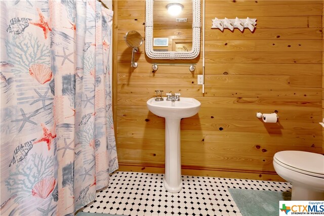 403 Bay St, Austwell, TX 77950 - bathroom with toilet, wooden walls, tile patterned flooring, and curtained shower