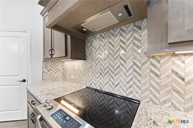 kitchen featuring light stone countertops, range, and premium range hood