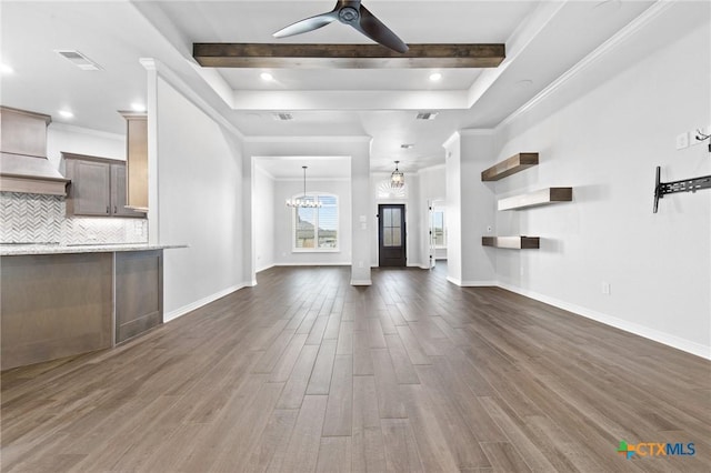 unfurnished living room featuring beamed ceiling, ceiling fan with notable chandelier, dark hardwood / wood-style floors, and ornamental molding