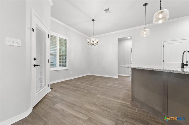 kitchen with light stone countertops, crown molding, dark hardwood / wood-style flooring, and pendant lighting