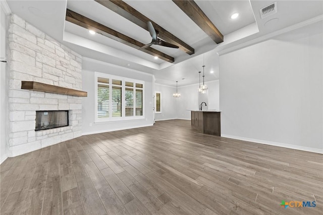 unfurnished living room with a fireplace, ceiling fan, dark wood-type flooring, and sink