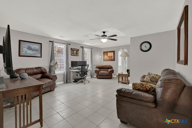 living room with light tile patterned floors, ceiling fan, arched walkways, visible vents, and baseboards