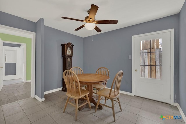 dining area featuring light tile patterned flooring, a ceiling fan, and baseboards