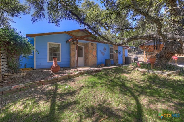 view of front of house featuring stone siding, a front yard, and cooling unit