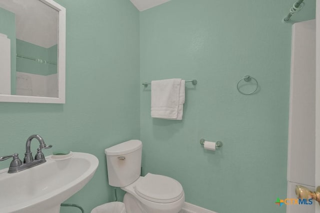 bathroom featuring a sink, toilet, and baseboards