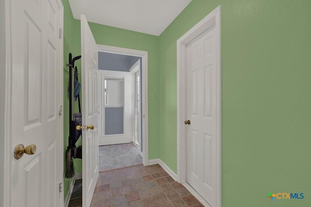 corridor with stone finish flooring and baseboards