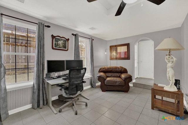 office area featuring arched walkways, visible vents, ceiling fan, and light tile patterned floors