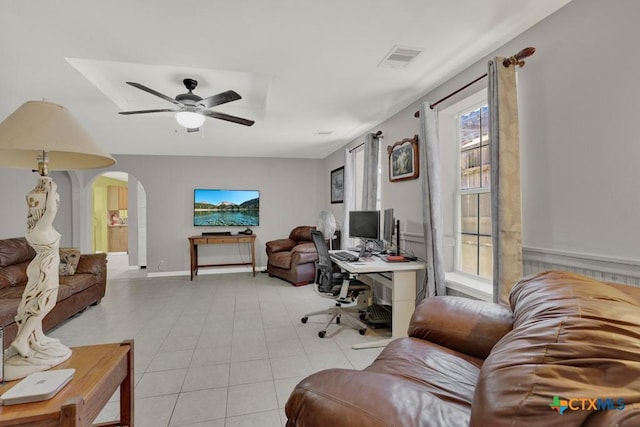 home office featuring arched walkways, light tile patterned flooring, visible vents, and a ceiling fan