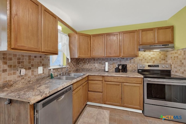 kitchen featuring tasteful backsplash, stainless steel appliances, light countertops, under cabinet range hood, and a sink