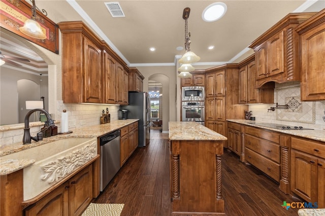 kitchen featuring crown molding, stainless steel appliances, decorative light fixtures, light stone countertops, and dark wood-type flooring