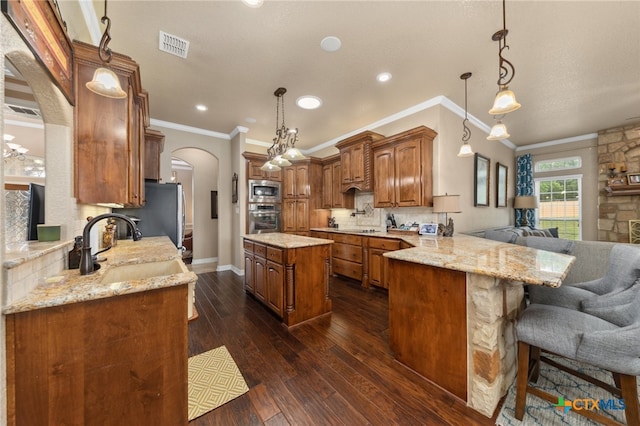 kitchen featuring stainless steel appliances, kitchen peninsula, hanging light fixtures, sink, and dark hardwood / wood-style floors