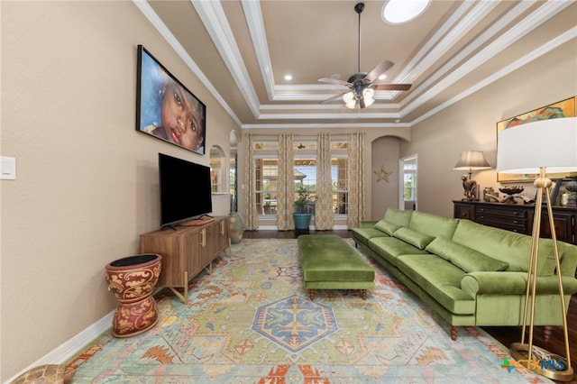 living room featuring light hardwood / wood-style flooring, a tray ceiling, ceiling fan, and crown molding