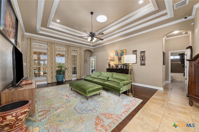 living room featuring crown molding, hardwood / wood-style flooring, ceiling fan, and a raised ceiling