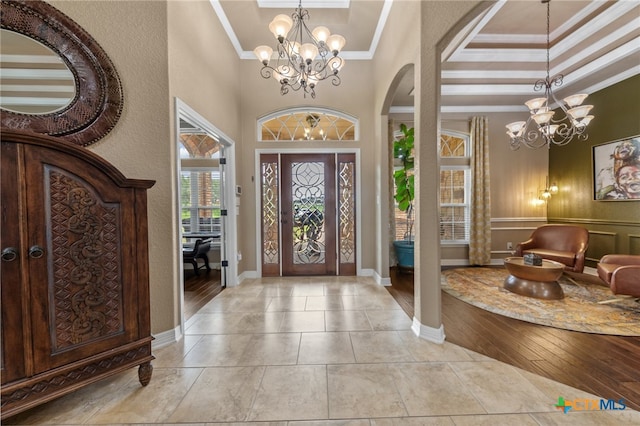 foyer with ornamental molding, light hardwood / wood-style floors, and an inviting chandelier