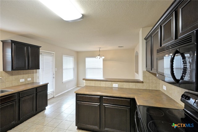 kitchen with light tile patterned flooring, black appliances, tasteful backsplash, hanging light fixtures, and a notable chandelier