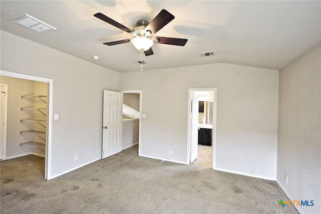 unfurnished bedroom featuring ceiling fan, carpet flooring, a closet, and a walk in closet