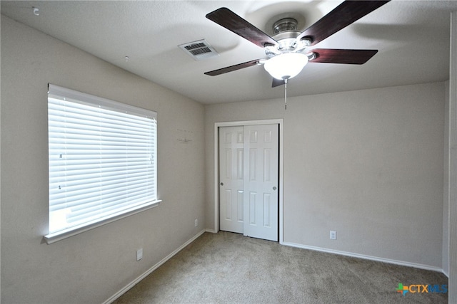 unfurnished bedroom with a closet, light carpet, and ceiling fan