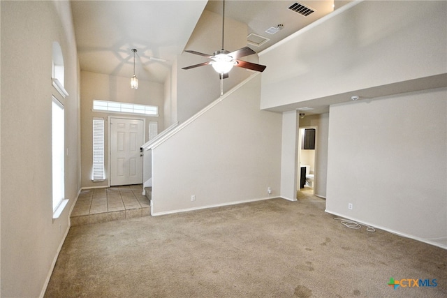 unfurnished living room with high vaulted ceiling, ceiling fan, light colored carpet, and a healthy amount of sunlight