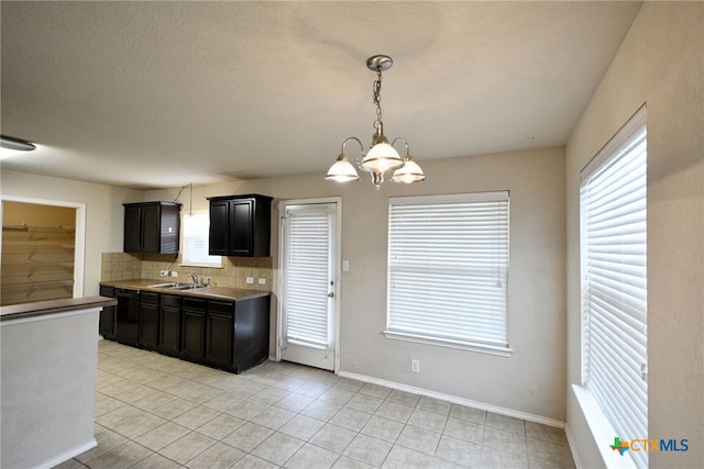 kitchen featuring sink, light tile patterned floors, decorative light fixtures, a chandelier, and decorative backsplash