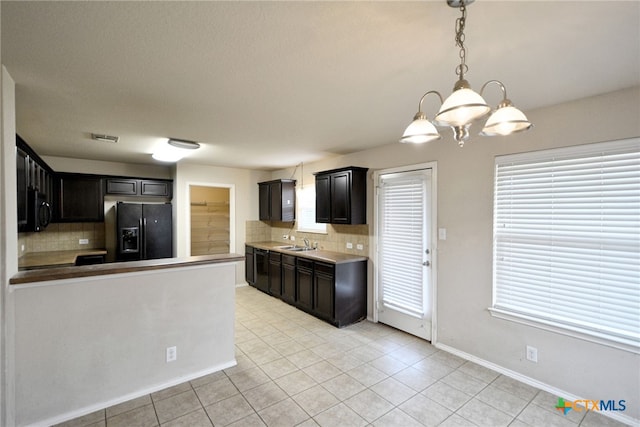 kitchen with decorative backsplash, black appliances, sink, and a notable chandelier