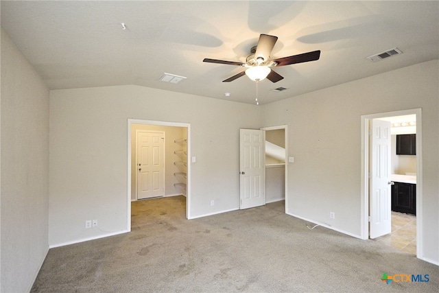 unfurnished bedroom with ensuite bathroom, ceiling fan, light carpet, and vaulted ceiling