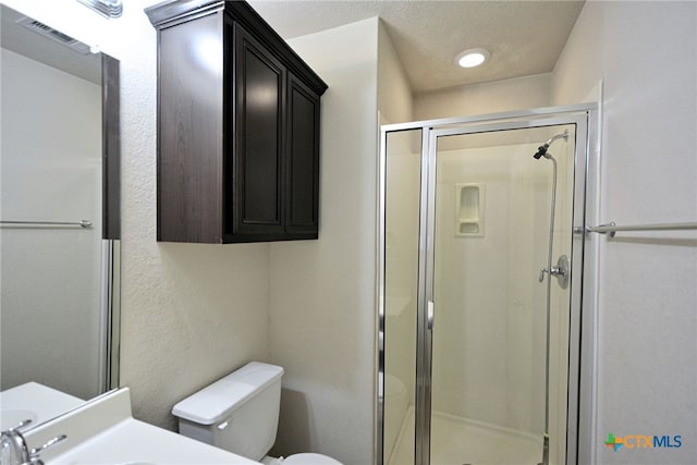 bathroom featuring vanity, walk in shower, a textured ceiling, and toilet