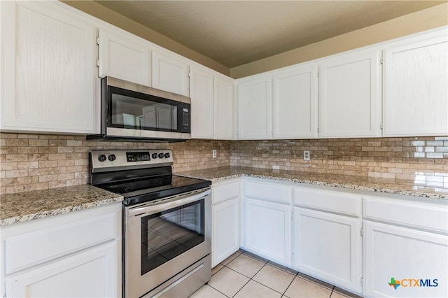 kitchen featuring decorative backsplash, white cabinetry, light tile patterned floors, and stainless steel appliances