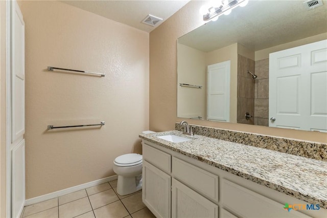 bathroom featuring toilet, a tile shower, vanity, and tile patterned floors