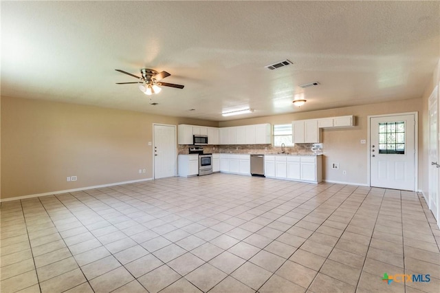 unfurnished living room with ceiling fan, sink, light tile patterned flooring, and a textured ceiling