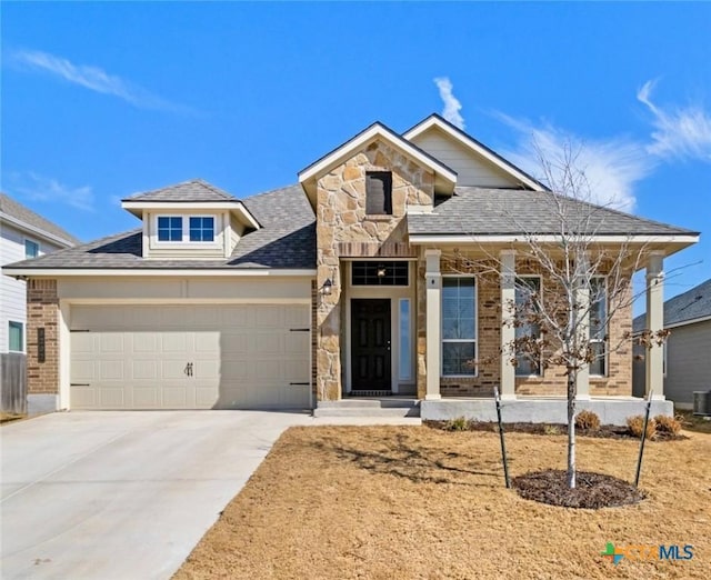 view of front of home with a garage, concrete driveway, brick siding, and stone siding