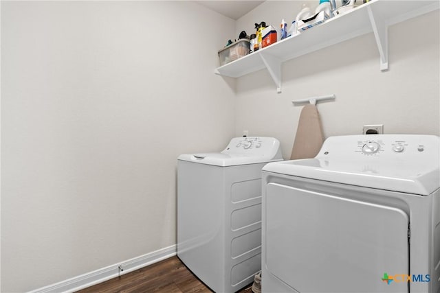 clothes washing area featuring dark wood-style flooring, laundry area, washer and clothes dryer, and baseboards