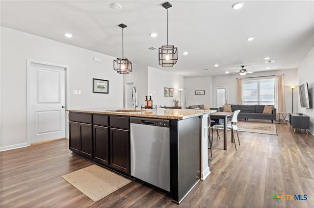 kitchen featuring a kitchen island with sink, wood finished floors, a sink, open floor plan, and stainless steel dishwasher