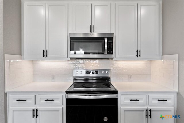 kitchen featuring stainless steel appliances, white cabinetry, and tasteful backsplash