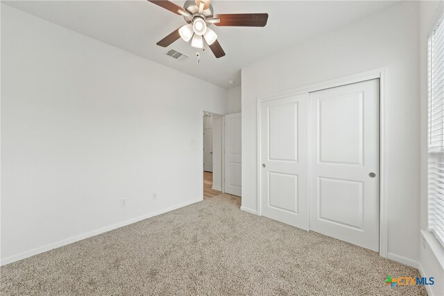 unfurnished bedroom featuring light colored carpet, ceiling fan, and a closet