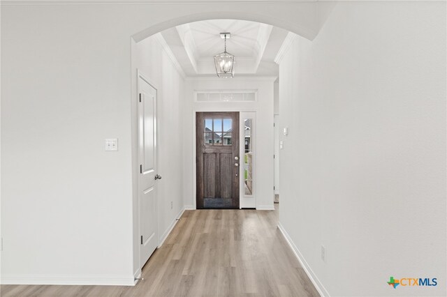 entrance foyer featuring an inviting chandelier, crown molding, and light hardwood / wood-style flooring