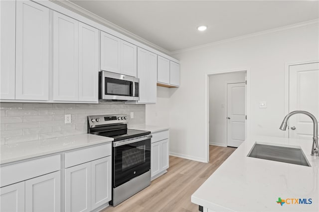 kitchen featuring light hardwood / wood-style floors, white cabinets, sink, backsplash, and appliances with stainless steel finishes