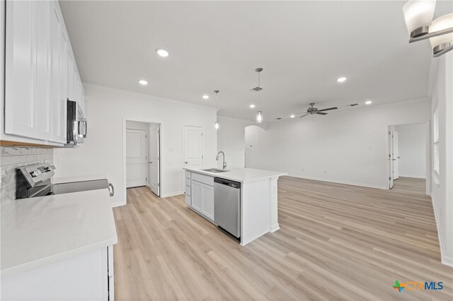 kitchen with white cabinetry, a center island with sink, appliances with stainless steel finishes, decorative light fixtures, and light hardwood / wood-style flooring