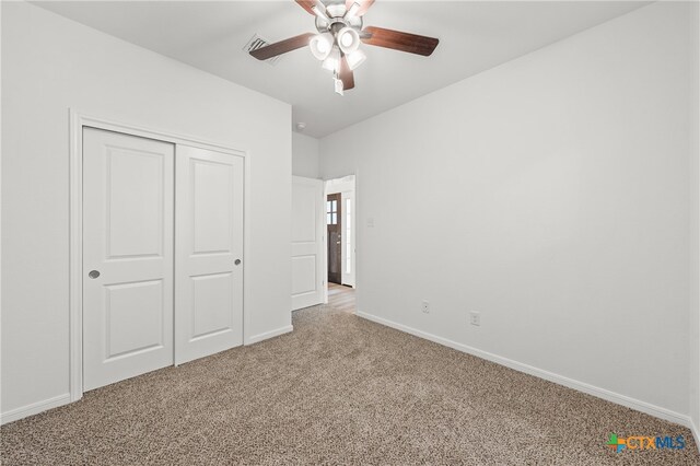 unfurnished bedroom with ceiling fan, light carpet, and a closet