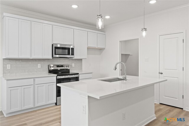 kitchen with a kitchen island with sink, stainless steel appliances, sink, and pendant lighting