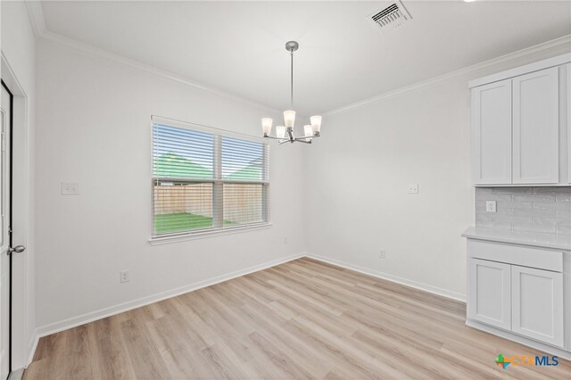 unfurnished dining area with ornamental molding, light wood-type flooring, and a notable chandelier