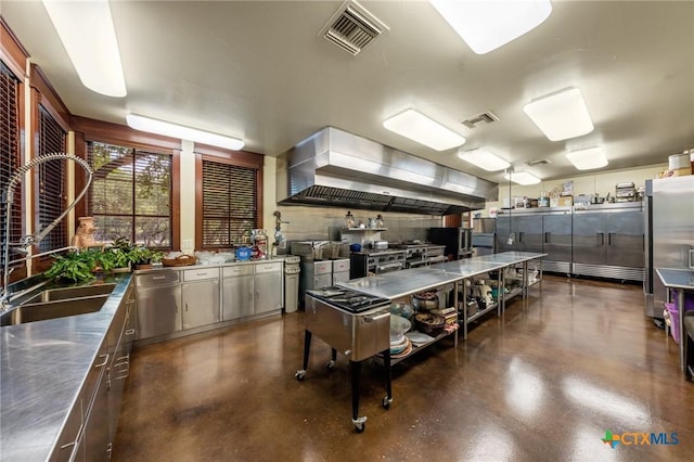 kitchen featuring stainless steel counters, wall chimney range hood, and sink