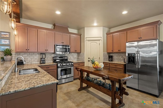 kitchen with sink, hanging light fixtures, decorative backsplash, light stone counters, and stainless steel appliances